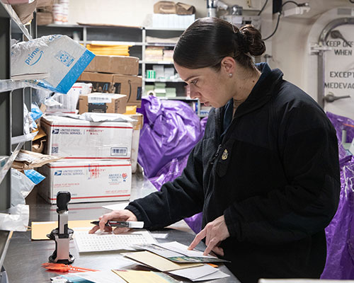 A Navy servicemember sorting postal packages.